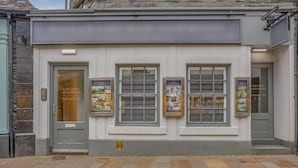 A building with a grey facade, three windows, and a door labeled 'Lake Road Apartments.' - 1 Bed in Keswick (oc-g35025) (Keswick)