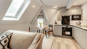 A compact kitchen with modern appliances, a dining area with a table and chairs, and a skylight. - 1 Bed in Keswick (oc-t35027) (Keswick)