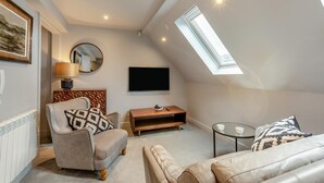 A modern loft bedroom with a sloped ceiling, a skylight, a bed, a TV, and a small table. - 1 Bed in Keswick (oc-t35027) (Keswick)