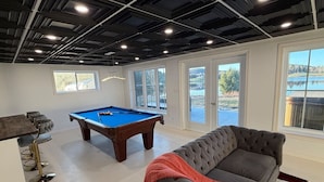 Une pièce spacieuse équipée d’une table de billard, d’un canapé et d’un coin bar.