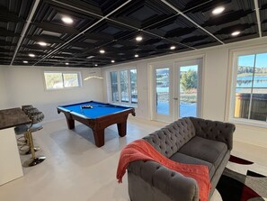 A spacious room with a pool table, a sofa, and a bar area.