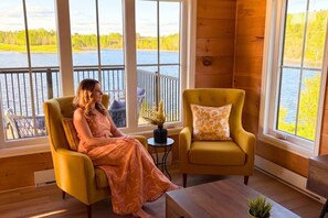 A room with a view of a lake, a yellow armchair, and a person seated.