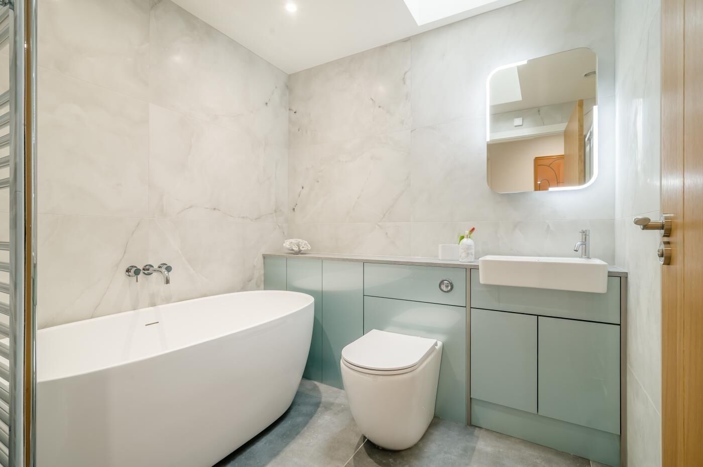 Un bany modern amb una banyera independent, un vàter i un lavabo amb mirall.