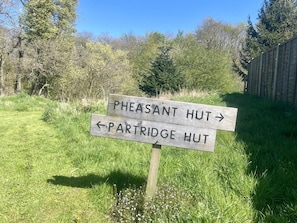 A wooden directional sign with arrows pointing to 'Pheasant Hut' and 'Partridge Hut.'