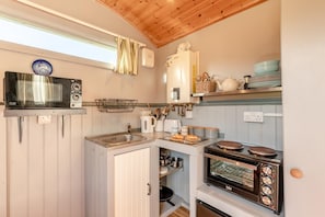 A compact kitchen with a microwave, oven, and sink.
