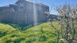 A wooden building with a sloped roof, a fenced yard, and a tree with blossoms. - 1 Bed in Lanercost (oc-t35009) (Burtholme)
