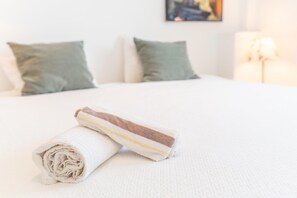 A neatly made bed with a rolled white towel and a striped towel on a white textured bedspread. - Coastal Escape with Private Pool for 6 (San José)