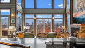Una habitación amplia con ventanas grandes, chimenea y zona de comedor con sillas y mesa.