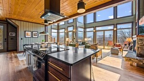 Cocina amplia con una isla grande, techo de madera y ventanas grandes que ofrecen vistas.