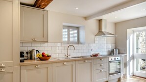 Eine moderne Küche mit weißen Schränken, einem eingebauten Backofen, einer Sp üle und einem Fenster über der Spüle.