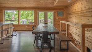 Een houten interieur met een lange eettafel, banken en uitzicht op het landschap.