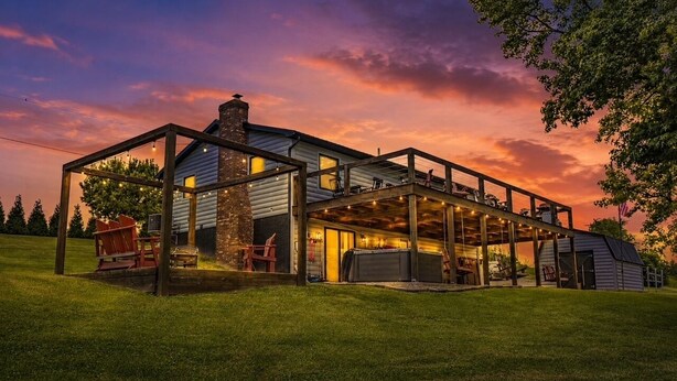 Een huis met een overdekte veranda, buitenmeubels en een garage.