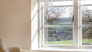 Une fenêtre donnant sur un paysage rural, avec des maisons et des arbres.