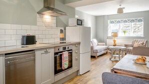 Une cuisine compacte équipée d’une cuisinière, d’un four, d’un four à micro-ondes et d’un petit coin repas avec une table et des chaises.