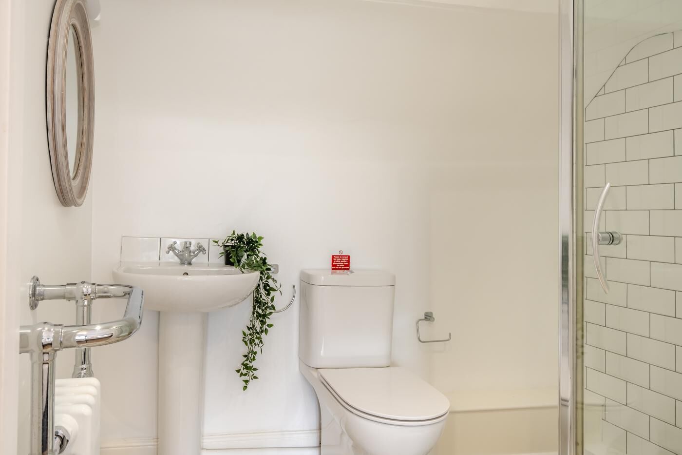Une salle de bain avec un lavabo, des toilettes et une douche, le tout de couleur blanche.
