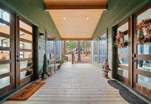 Eine überdachte Veranda mit Holzboden, großen Glasfenstertüren und einer Fußmatte.