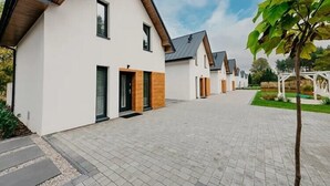 A row of modern, single-story houses with a paved driveway and a small garden area. - Comfortable holiday home, sauna, jacuzzi (Kopalino)