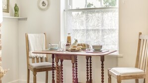 Una mesa de comedor con sillas, una ventana con vistas, un florero y un plato en la pared.