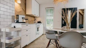 Eine moderne Küche mit weißen Schränken, einem eingebauten Backofen und einem Essbereich mit Tisch und Stühlen.