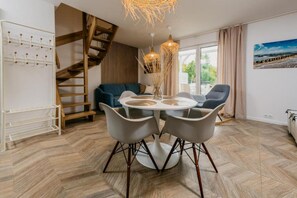 Ein modernes Wohnzimmer mit einem runden Esstisch, zwei Stühlen, einer Couch und einer Treppe.