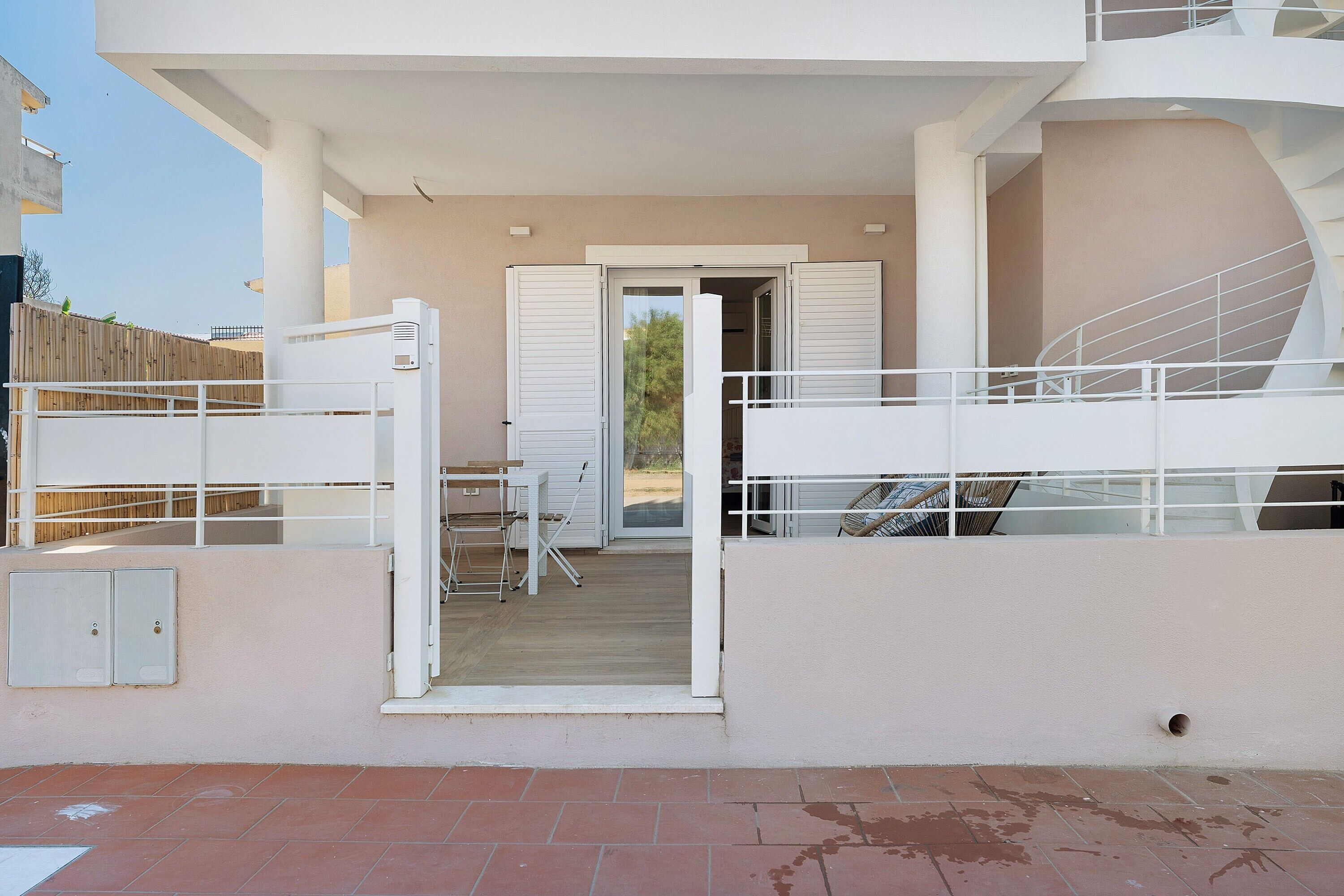 Un bâtiment moderne doté d’un balcon, d’un escalier et d’une porte donnant sur un espace intérieur.