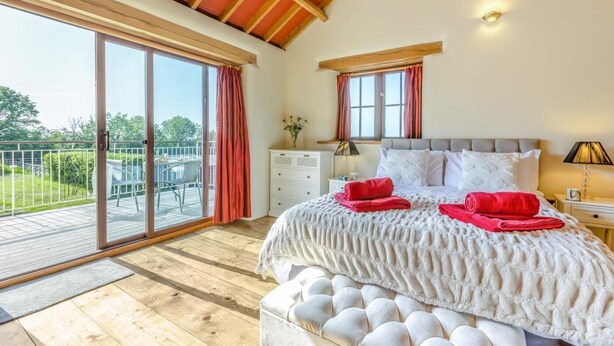 A bedroom with a large bed, a nightstand, a dresser, and a window with curtains. - 1 Bed in East Chilla (oc-o34984) (Black Torrington)