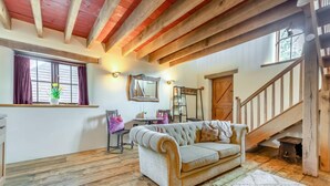A cozy room with a sofa, a dining table, and a staircase. - 1 Bed in East Chilla (oc-o34984) (Black Torrington)
