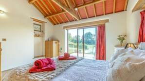 A bedroom with a large bed, a wooden wardrobe, a window with a view, and a ceiling with exposed beams. - 1 Bed in East Chilla (oc-o34984) (Black Torrington)