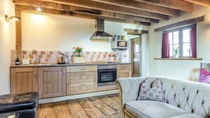 A kitchen with wooden cabinets, a stove, and a microwave. - 1 Bed in East Chilla (oc-o34984) (Black Torrington)