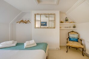Ein Schlafzimmer mit einem Bett, einem Sessel, einer Ablage mit Dekoration und einem Fenster mit Blick.
