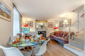 Ein Essbereich mit einem für das Frühstück gedeckten Tisch, einer Couch und einer Treppe.