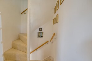 Eine Treppe mit beigefarbenem Teppich, einem hölzernen Geländer und einer Wandleuchte.