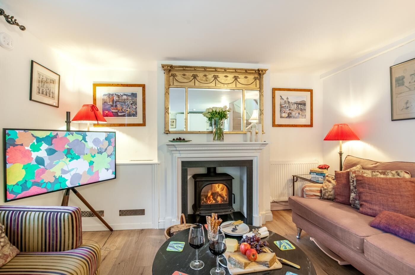 A living room with a fireplace, a sofa, a television, and a dining table with food and drinks.
