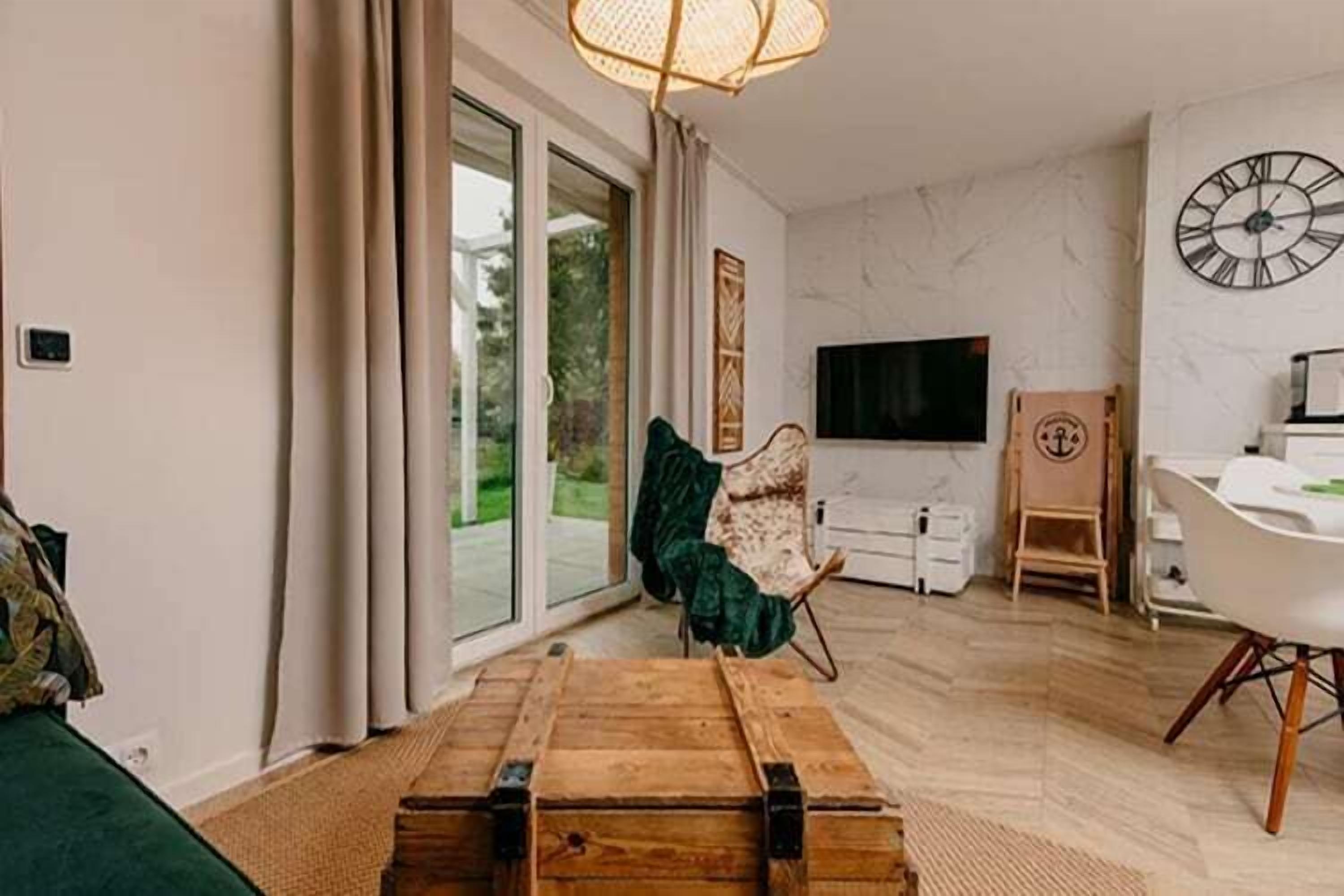 Un salon moderne comprenant un canapé, une commode en bois, un fauteuil, une table à manger et un téléviseur.
