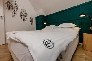 Ein Bett mit weißer Bettdecke, einem türkisfarbenen Kopfteil und einer Wand mit Traumfängern.