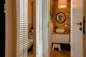 Une salle de bain avec un lavabo blanc, un miroir et un mur en bois.