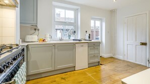 Een moderne keuken met een gasfornuis, een vaatwasser en een raam.