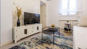 A modern living room with a flat-screen TV, a white cabinet, a black coffee table, and a patterned rug. - Central Haven near Museums (Madrid)