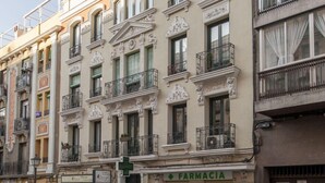 A multi-story building with ornate architectural details, a pharmacy on the ground floor, and balconies with iron railings. - Central Haven near Museums (Madrid)