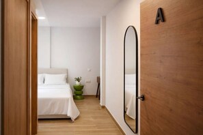 Een hotelkamer met een bed, een spiegel, een houten deur en een kleine plant.