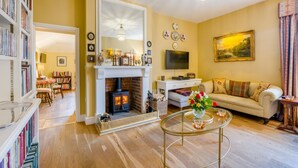 Una sala de estar acogedora con chimenea, un sofá, un televisor y una estantería.