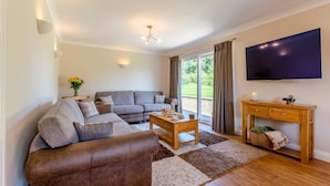 A living room with a sofa, coffee table, TV, and a desk. - 4 Bed in Ireby (oc-p34997) (Ireby)