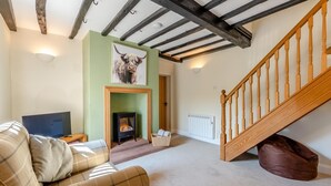 A living room with a sofa, a fireplace, a television, and a staircase. - 4 Bed in Ireby (oc-p34997) (Ireby)