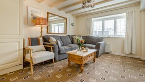 Ein Wohnzimmer mit einer Couch, einem Sessel, einem Holztisch und einem Spiegel.