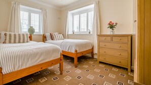 Ein Schlafzimmer mit zwei hölzernen Betten, einem Schminktisch und einer Vase mit Blumen.