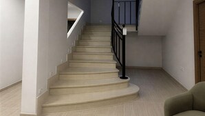 Eine Treppe mit schwarzer Geländer, beigen Stufen und einem hellen Boden.