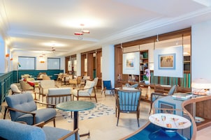 Un hall de hotel con una zona de estar, un bar y un comedor.