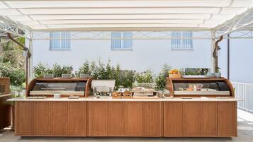 An outdoor buffet setup with a wooden counter, various food items, and a white canopy.
