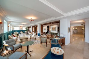 A spacious lobby with multiple seating areas, including sofas and chairs, a coffee table, and a reception desk.