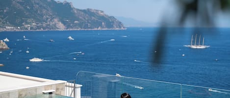 Eine Person in einem klaren, blauen Pool mit Blick auf das Meer und Boote.